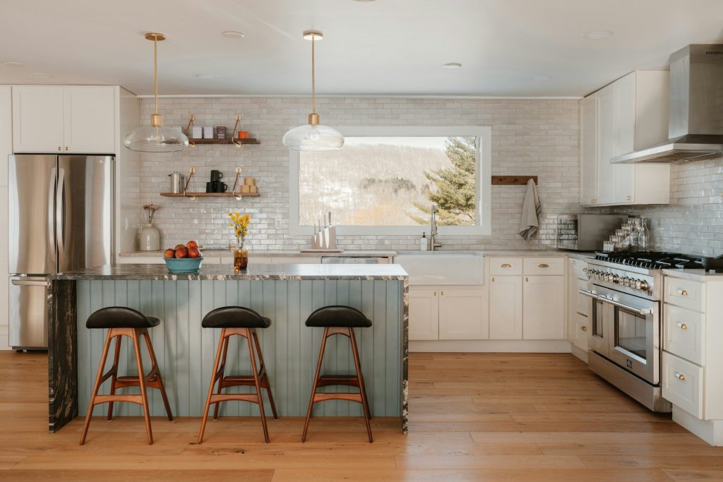 A wide bright kitchen with an island and a stainless range against the far wall