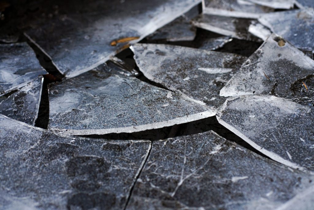 A shattered sheet of dark ceramic cooktop glass broken into large angular pieces