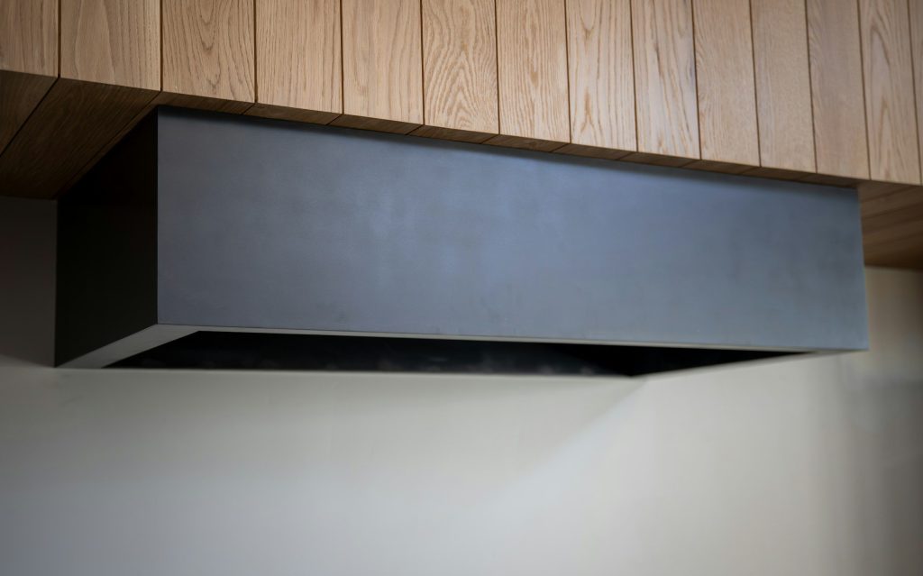 A plain slim range hood canopy fitted under a run of wood wall cabinets
