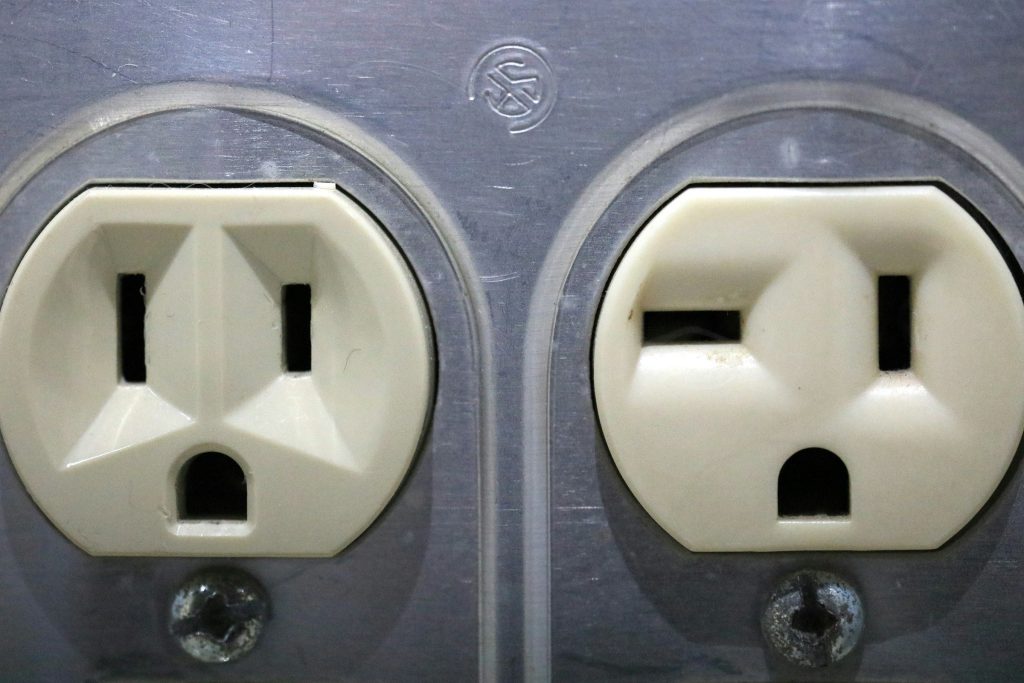 Two aged electrical outlets in a discolored wall plate