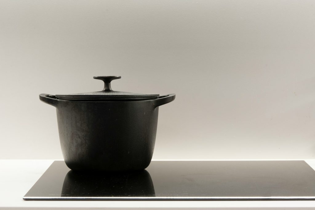 A heavy lidded casserole standing on an induction cooktop with the surrounding zones dark