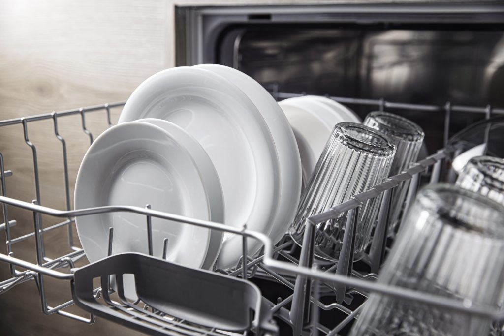 Plates and glasses standing in a dishwasher basket at the end of a cycle