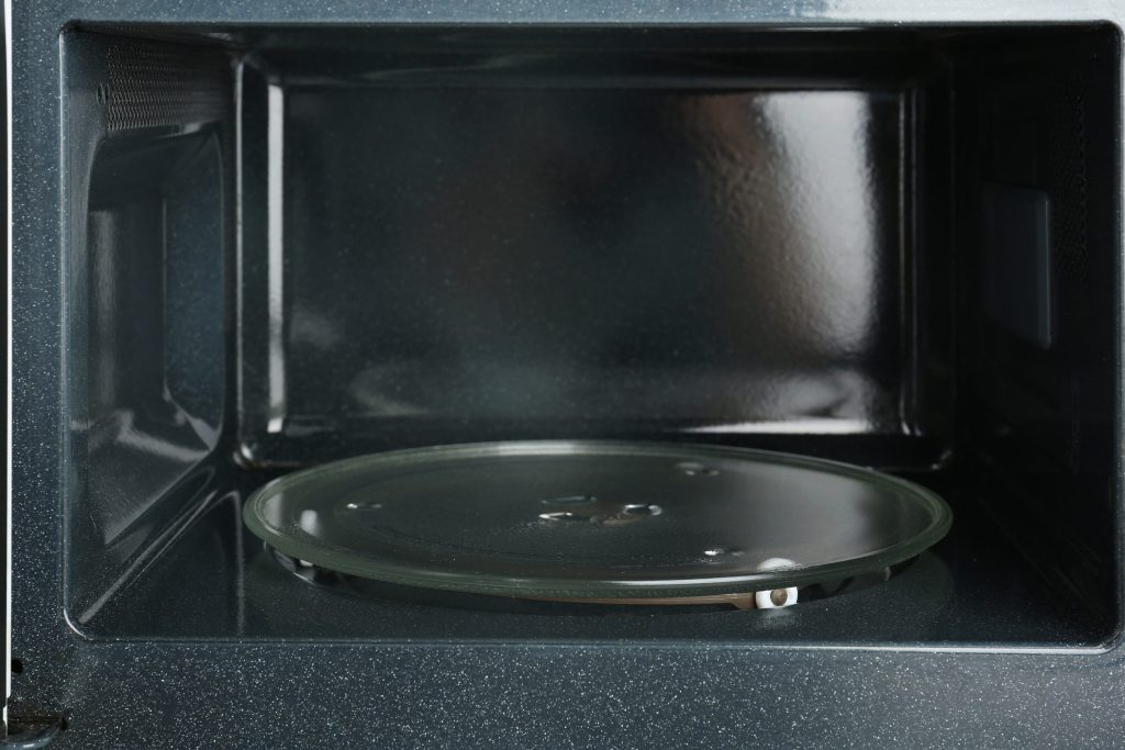 The empty interior of a microwave with its glass turntable in place and the door open